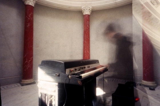 An electric piano between painted columns, from the photographs in the discbox